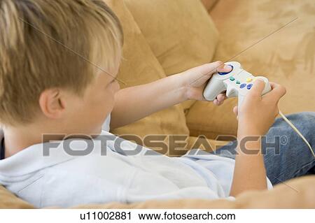 Young boy in living room with video game controller View Large Photo Image Stock Image - Young boy in living room with video game controller. Fotosearch