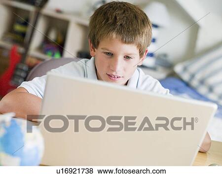 Stock Photo - Young Boy Using Laptop In His Bedroom. Fotosearch
