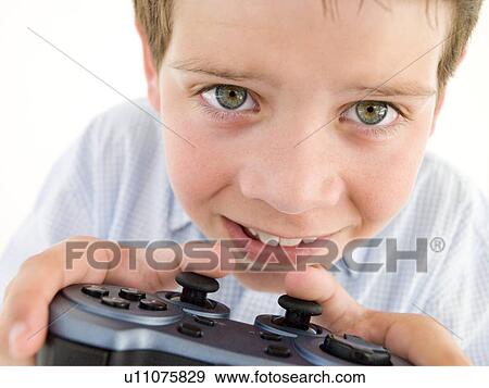 Stock Photo - Young boy using videogame controller smiling. Fotosearch