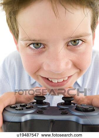 Stock Photo - Young boy using videogame controller smiling. Fotosearch