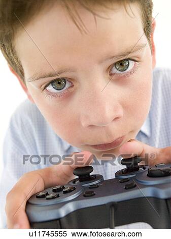 Stock Photography - Young boy using videogame controller and concentrating. Fotosearch