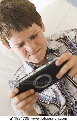 Young boy with handheld game indoors looking unhappy View Large Photo Image Stock Photography - Young boy with handheld game indoors looking unhappy. Fotosearch