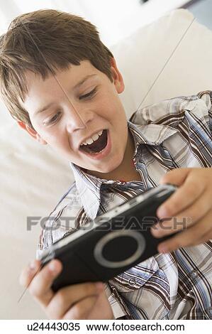 Young boy with handheld game indoors View Large Photo Image Stock Photography - Young boy with handheld game indoors. Fotosearch