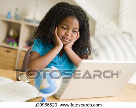 Stock Image - Young Girl Doing Her Homework On A Laptop. Fotosearch