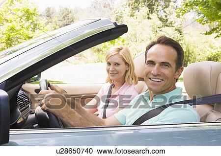 Stock Image - Couple in convertible car smiling. Fotosearch