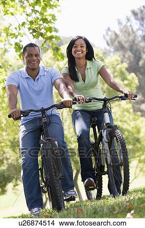Couple on bikes outdoors smiling View Large Photo Image Picture - Couple on bikes outdoors smiling. Fotosearch