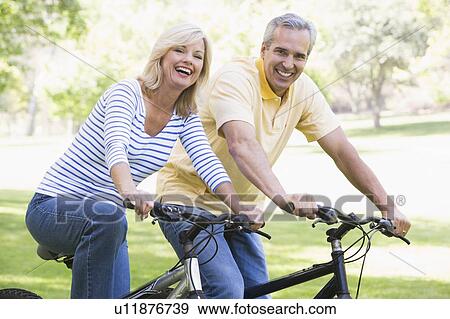 Couple on bikes outdoors smiling View Large Photo Image Stock Photo - Couple on bikes outdoors smiling. Fotosearch