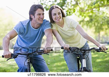 Couple on bikes outdoors smiling View Large Photo Image Stock Photograph - Couple on bikes outdoors smiling. Fotosearch