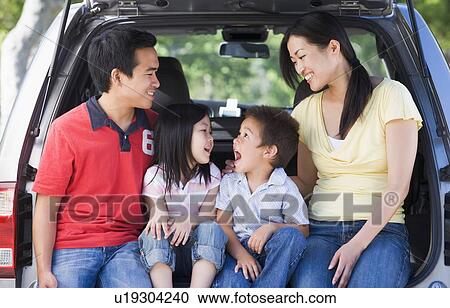 Stock Image - Family sitting in back of van smiling. Fotosearch