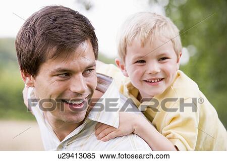Stock Photography - Father giving son piggyback ride outdoors smiling. Fotosearch
