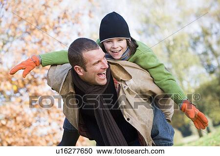 Father outdoors piggybacking son and smiling (selective focus) View Large Photo Image Stock Image - Father outdoors piggybacking son and smiling (selective focus). Fotosearch