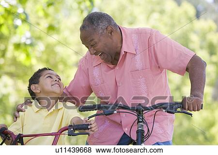 Grandfather and grandson on bikes outdoors smiling View Large Photo Image Stock Photo - Grandfather and grandson on bikes outdoors smiling. Fotosearch