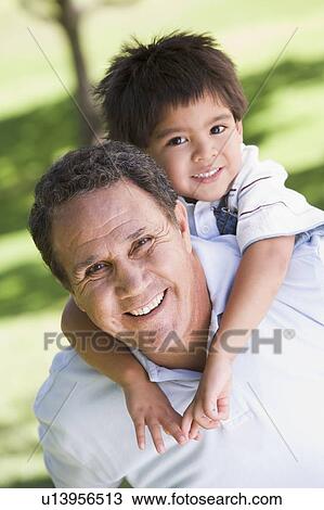 Stock Image - Grandfather piggryback riding grandson.. Fotosearch