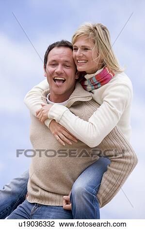 man giving woman piggyback ride outdoors smiling View Large Photo Image Stock Image - man giving woman piggyback ride outdoors smiling. Fotosearch