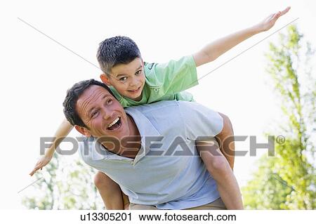 Man giving young boy piggyback ride outdoors smiling View Large Photo Image Stock Image - Man giving young boy piggyback ride outdoors smiling. Fotosearch