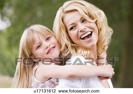 Stock Image - Mother holding daughter outdoors smiling. Fotosearch