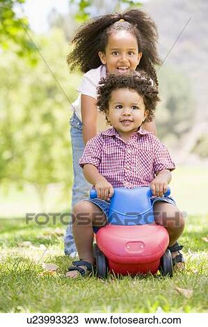 Sister pushing brother on toy with wheels smiling View Large Photo Image Stock Image - Sister pushing brother on toy with wheels smiling. Fotosearch