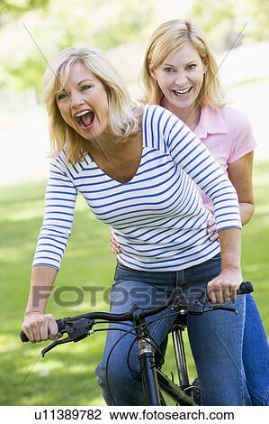 Two friends on one bike outdoors smiling View Large Photo Image Stock Image - Two friends on one bike outdoors smiling. Fotosearch