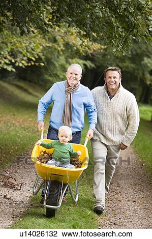 Two men walking on path outdoors pushing baby in wheelbarrow and smiling (selective focus) View Large Photo Image Stock Image - Two men walking on path outdoors pushing baby in wheelbarrow and smiling (selective focus). Fotosearch