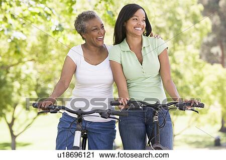 Two women on bikes outdoors smiling View Large Photo Image Stock Image - Two women on bikes outdoors smiling. Fotosearch