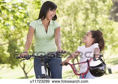 Woman and young girl on bikes outdoors smiling View Large Photo Image Stock Photo - Woman and young girl on bikes outdoors smiling. Fotosearch