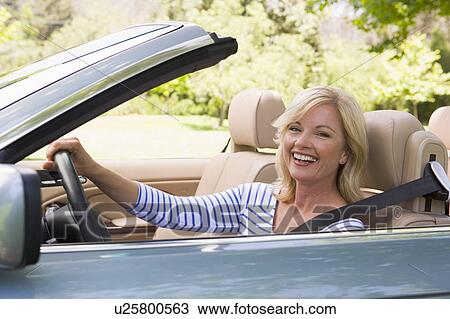 Stock Image - Woman in convertible car smiling. Fotosearch