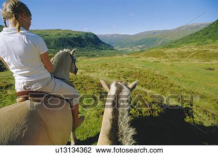 Woman outdoors riding horse in scenic location with another horse beside her View Large Photo Image Stock Image - Woman outdoors riding horse in scenic location with another horse beside her. Fotosearch
