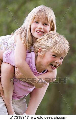 Young boy giving young girl piggyback outdoors smiling View Large Photo Image Stock Photo - Young boy giving young girl piggyback outdoors smiling. Fotosearch