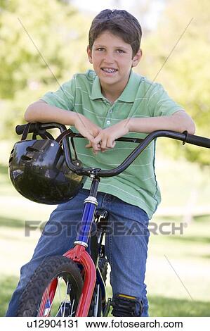 Young boy on bicycle outdoors smiling View Large Photo Image Stock Image - Young boy on bicycle outdoors smiling. Fotosearch
