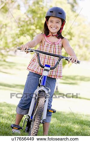 Young girl on bicycle outdoors smiling View Large Photo Image Stock Photo - Young girl on bicycle outdoors smiling. Fotosearch