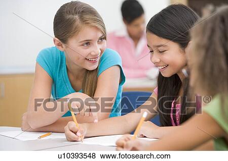 Students in class writing and talking with teacher in background (selective focus) View Large Photo Image Stock Photo - Students in class writing and talking with teacher in background (selective focus). Fotosearch