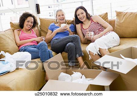 Three girl friends relaxing with coffee by boxes in new home smiling View Large Photo Image Stock Image - Three girl friends relaxing with coffee by boxes in new home smiling. Fotosearch