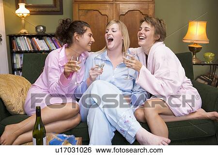 Stock Photograph - Three woman in night clothes sitting at home drinking wine. Fotosearch
