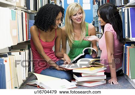 Stock Photo - Three women sitting on floor in library with books. Fotosearch
