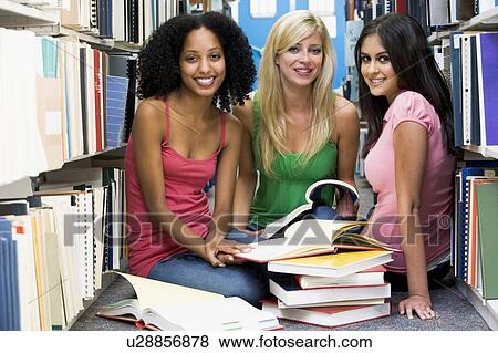 Stock Photo - Three women sitting on floor in library with books. Fotosearch