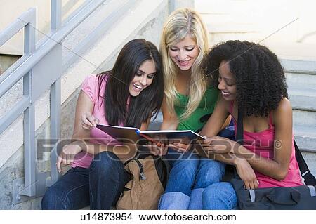 Three women sitting on staircase outdoors looking at notebook (high key) View Large Photo Image Picture - Three women sitting on staircase outdoors looking at notebook (high key). Fotosearch