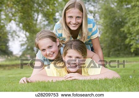 Three young girl friends piled on each other outdoors smiling View Large Photo Image Stock Image - Three young girl friends piled on each other outdoors smiling. Fotosearch