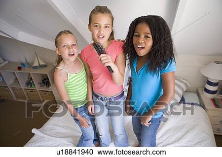 Three Young Girls Standing On A Bed, Singing Into A Hairbrush View Large Photo Image Stock Image - Three Young Girls Standing On A Bed, Singing Into A Hairbrush. Fotosearch