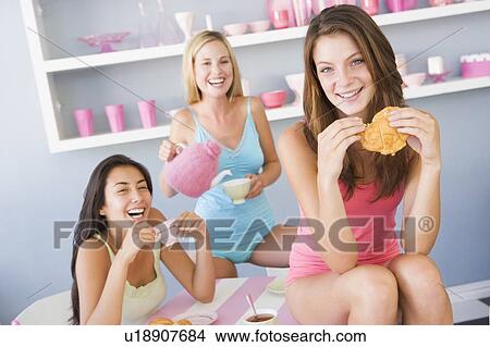 Three young woman sitting at a table having tea and a snack View Large Photo Image Picture - Three young woman sitting at a table having tea and a snack. Fotosearch