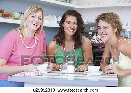 Three young woman sitting at a table and drinking tea View Large Photo Image Stock Image - Three young woman sitting at a table and drinking tea. Fotosearch