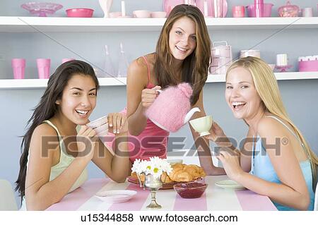 Three young woman sitting at a table having tea and a snack View Large Photo Image Stock Photo - Three young woman sitting at a table having tea and a snack. Fotosearch