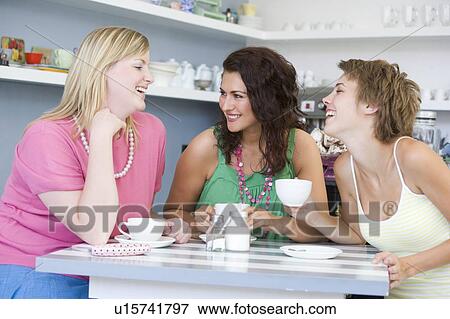 Stock Photo - Three young woman sitting at a table and drinking tea. Fotosearch