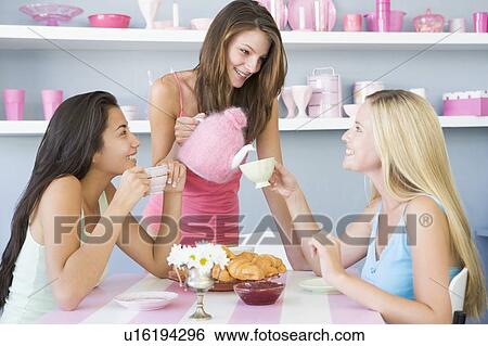 Stock Photograph - Three young woman sitting at a table having tea and a snack. Fotosearch