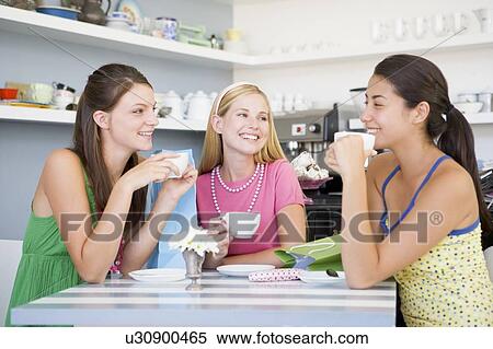 Three young woman sitting at a table and drinking tea View Large Photo Image Stock Photography - Three young woman sitting at a table and drinking tea. Fotosearch