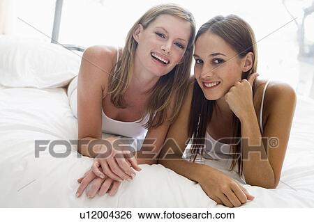 Two women lying in bed smiling View Large Photo Image Stock Photograph - Two women lying in bed smiling. Fotosearch