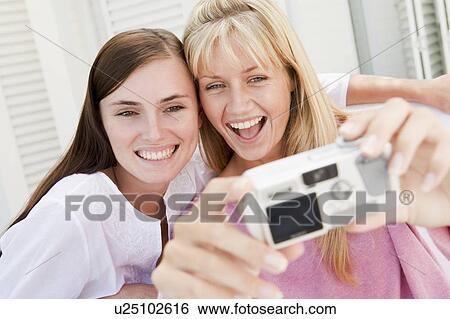 Two women on patio using digital camera smiling View Large Photo Image Stock Photograph - Two women on patio using digital camera smiling. Fotosearch