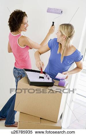 Stock Photography - Two women painting room in new home smiling. Fotosearch