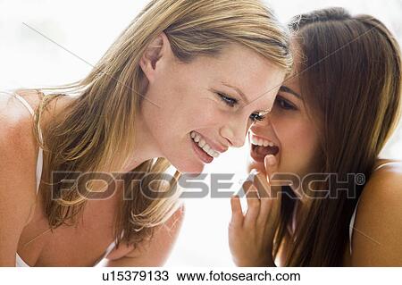 Stock Image - Two women whispering and smiling. Fotosearch