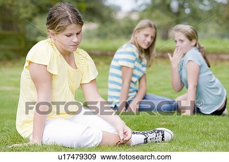 Stock Photo - Two young girls bullying other young girl outdoors. Fotosearch