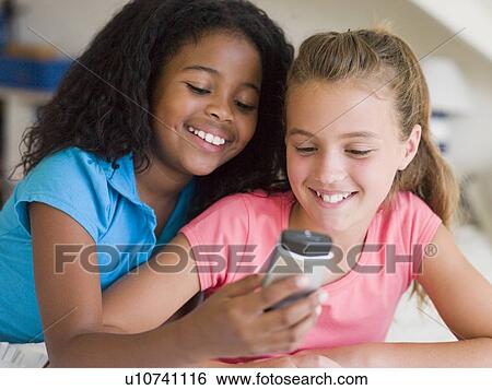 Stock Photograph - Young Girls Playing With A Cellphone. Fotosearch